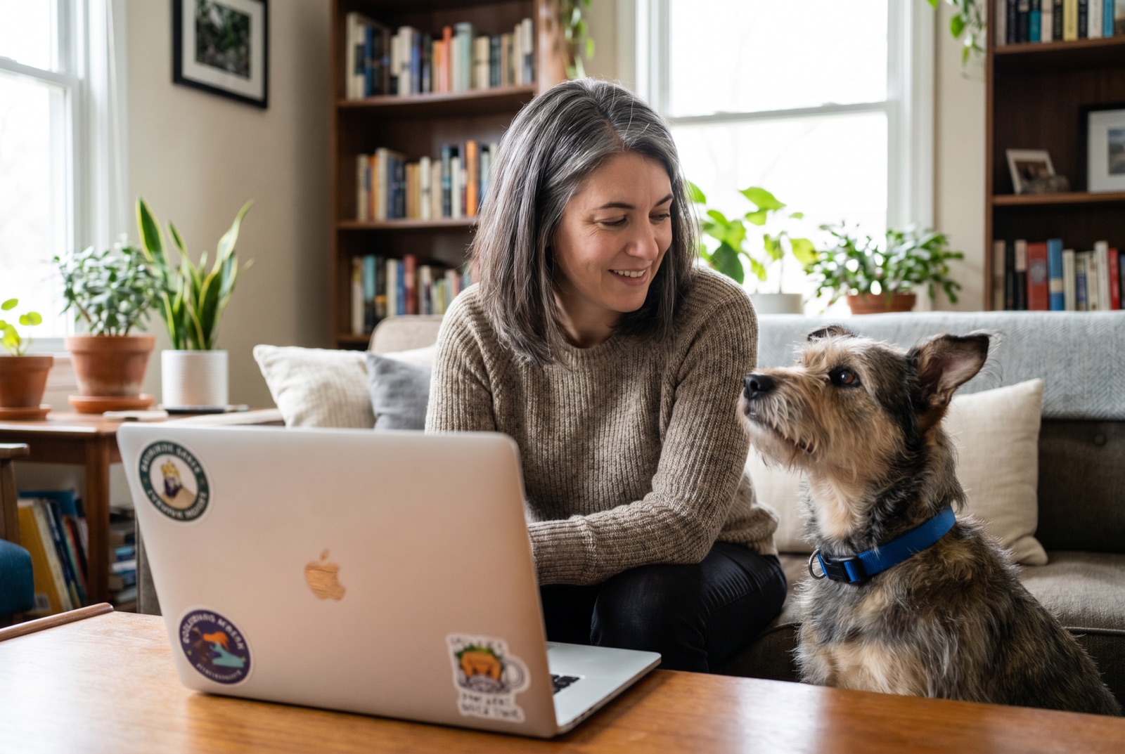 Woman using a laptop with her dog beside her